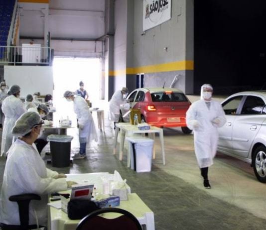 profissionais com equipamentos de proteção no centro de multiuso de são josé andando ao lado de carros