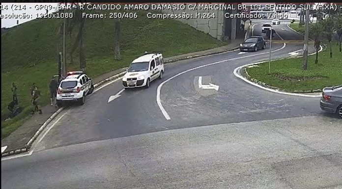 imagem de câmera de segurança do trevo de barreiros onde há viatura da pm sobre calçada, com policias e outros homens ao lado; carro passando