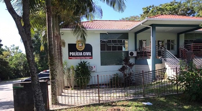 prédio branco com letreiro da delegacia de polícia