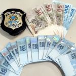 Dinheiro falso e distintivo da polícia em cima de uma mesa