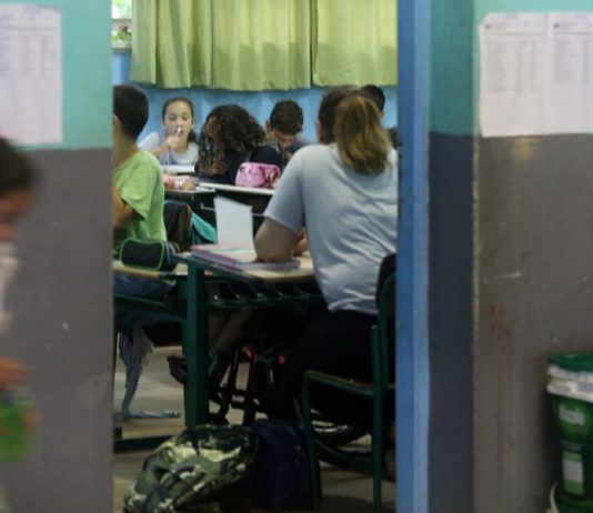 Ideb de Santa Catarina tem melhora no Ensino Médio, queda no Fundamental e metas não batidas alunos vistos sentados nas carteiras de sala de aula por entre a porta
