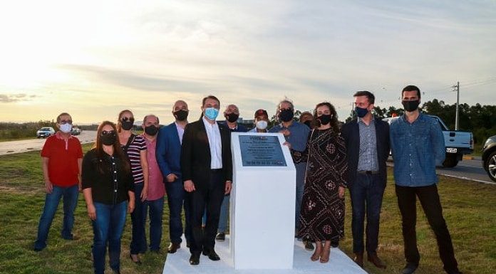 governador de máscara ao lado de placa em monumento com outras pessoas de máscara em volta