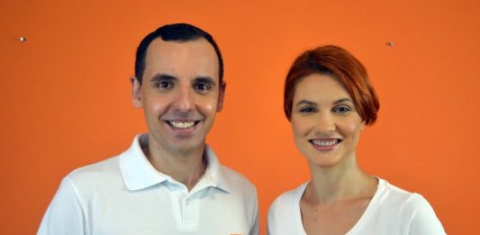 Partido Novo confirma Thiago Paulo como pré-candidato a prefeito em São José thiago paulo e dayanne borges olham sorridentes para a câmera usando camisetas do partido; parede laranja de fundo