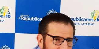 antônio lemos visto um pouco de lado; ele está de óculos e barba, usando uma camisa azul; atrás há um painel com logos do partido republicanos