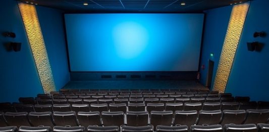 sala de cinema vista do alto com todas as cadeiras vazias e tela azul ao fundo - cinemas reabrem