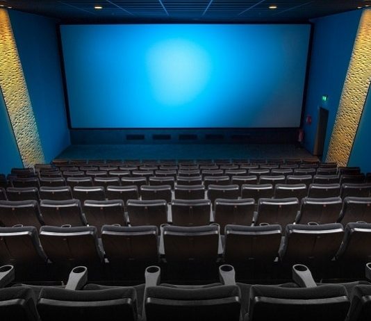 sala de cinema vista do alto com todas as cadeiras vazias e tela azul ao fundo - cinemas reabrem