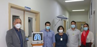 cinco pessoas usando máscara posam para a foto no corredor do hospital ao lado do respirador