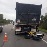 moto caída atrás do caminhão, parados na pista direita e com cones em volta