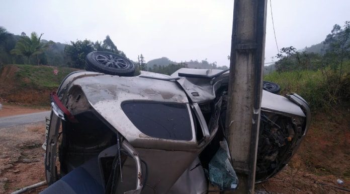 carro tombado de lado com teto batido em poste, destruído