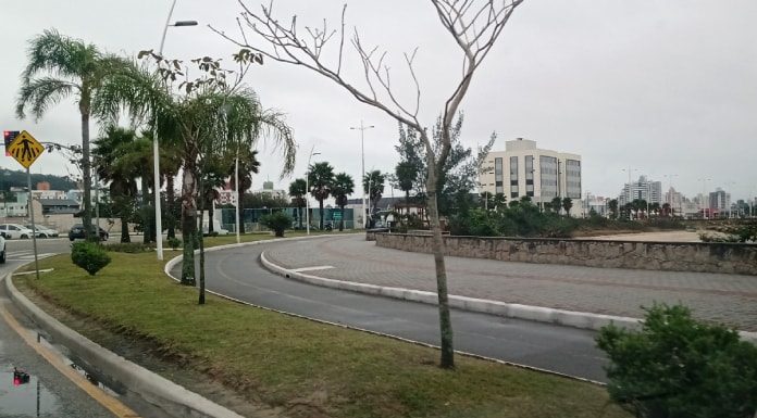 curva do calçadão da beira-mar de são josé junto com ciclovia; não há ninguém; dia nublado; árvores ao longo da orla; prédios ao fundo