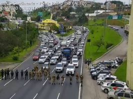 Motoboys fazem manifestação contra fiscalização; polícias fecharam entrada da ilha linha de policiais em pé cruzando barreira na pista e grandes filas paradas na via expressa
