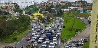 linha de policiais em pé cruzando barreira na pista e grandes filas paradas na via expressa