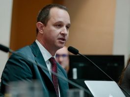 jorge tasca usa terno e fala ao microfone