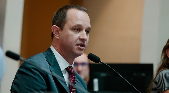 jorge tasca usa terno e fala ao microfone