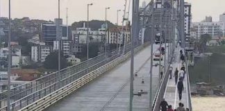 videomonitoramento da ponte mostra pessoas andando em passarela à direita e carro ao fundo no meio da ponte; continente do outro lado