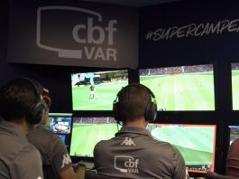 O VAR deve ser melhor operado para não atrapalhar o futebol homens vistos de costas sentados à frente de monitores com imagens de jogo e inscrição "CBF VAR" em suas costas