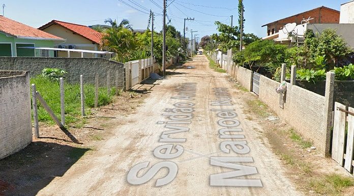 Mulher de 24 anos: imagem da servidão com rua de terra e nome da servidão escrito por cima; casas em volta