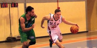 jogador de verde acompanha jogador de branco com a bola de basquete na quadra