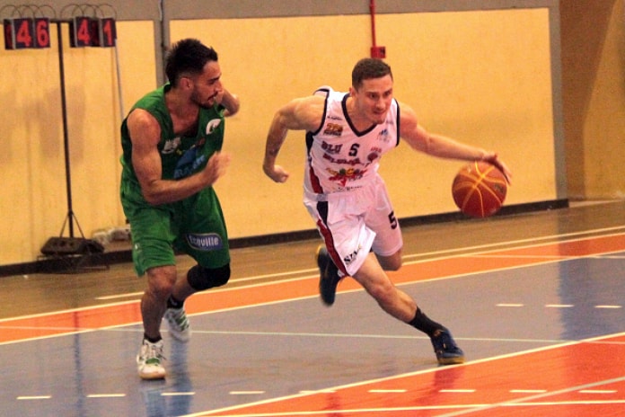 jogador de verde acompanha jogador de branco com a bola de basquete na quadra