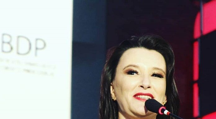 claudia prudência discursa em tribuna com microfone à frente