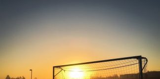pôr do sol visto no meio de uma trave de futebol com rede