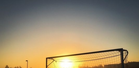 pôr do sol visto no meio de uma trave de futebol com rede