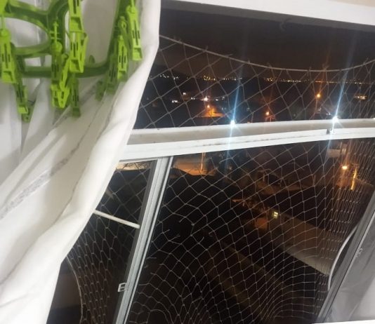 janela quebrada com tela de proteção de crianças com as batentes retorcidas