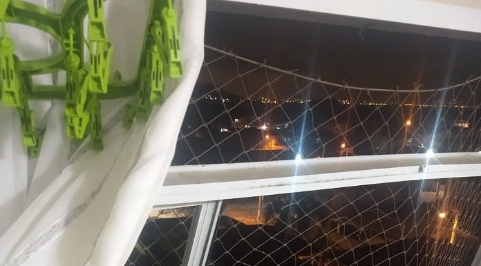 janela quebrada com tela de proteção de crianças com as batentes retorcidas