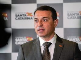 “Acreditamos no arquivamento definitivo”, diz Moisés sobre o impeachment moisés falando; painel de logos do governo ao fundo