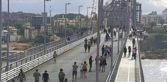 pessoas andando na ponte hercílio luz pelas passarelas e vão central