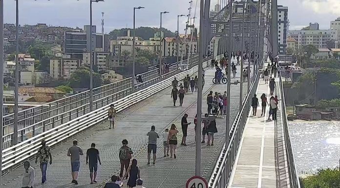 pessoas andando na ponte hercílio luz pelas passarelas e vão central