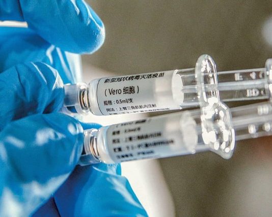 Ministro Pazuello diz que 46 milhões de doses da Coronavac chegam em janeiro pessoas usando luva azul cirúrgica segura duas seringas de vacina com dizeres em chinês