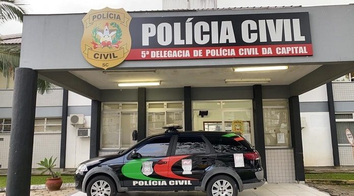 fachada da delegacia com viatura estacionada sob a marquise