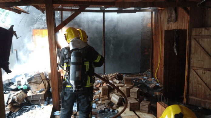 Bombeiros militares apagando o incêndio dentro da fábrica de velas