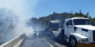 Caminhão branco tombado e queimado na pista