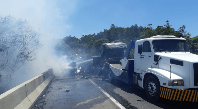 Caminhão branco tombado e queimado na pista