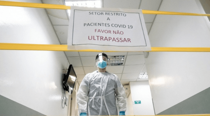 Área restrita em hospital, com cartaz, fitas amarelas e médico equipado contra o coronavírus