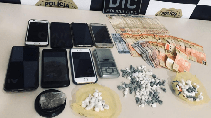 sobre uma mesa apreensões do delivery de cocaína: oito celulares, dinheiro e cocaína