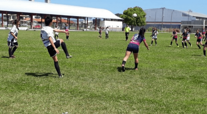 Meninas jogando futebol de campo ao ar livre