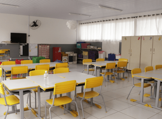 Sala de aula, com mesas e cadeiras vazias