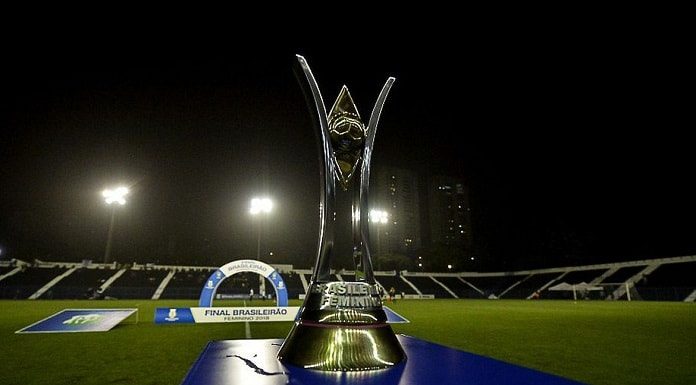 taça do campeonato brasileiro feminino sobre palanque em campo de futebol à noite