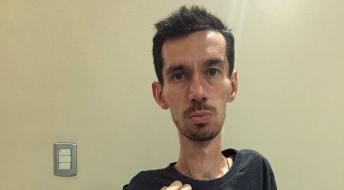 alisson mostra um papel para foto escrito "parem!!!"; ele olha sério para a câmera