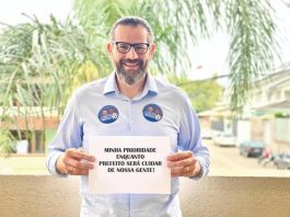 lemos posa sorridente para a foto com uma placa dizendo: Minha prioridade enquanto prefeito será cuidar de nossa gente!