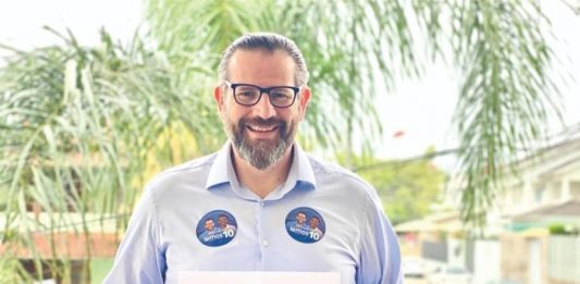Minha prioridade enquanto prefeito será cuidar de nossa gente lemos posa sorridente para a foto com uma placa dizendo: Minha prioridade enquanto prefeito será cuidar de nossa gente!