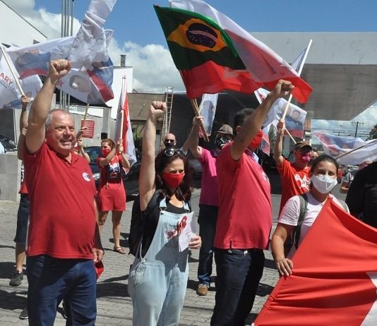 Vamos juntos construir uma São José para o povo ary martins levanta a mão cerrada em comemoração com diversos correligionários em volta com bandeiras