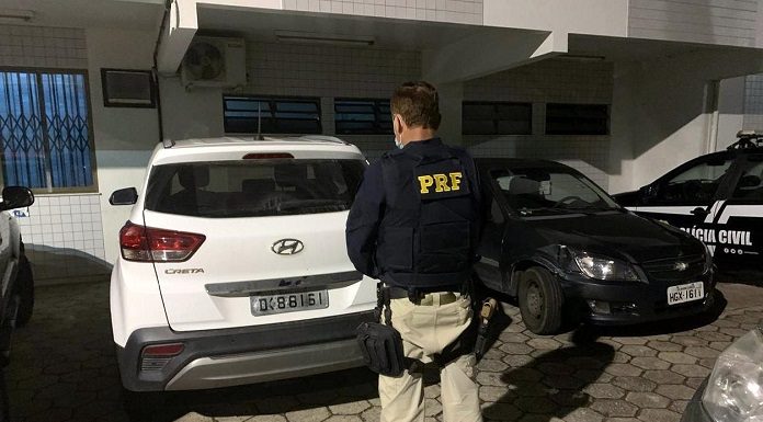 Policial com uniforme da PRF de costas em frente ao veículo