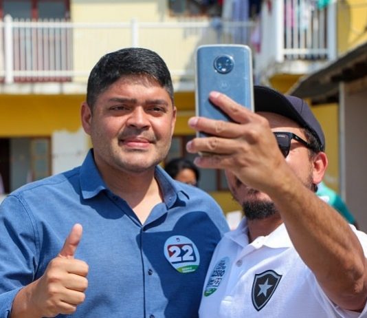 clonny sorri e faz sinal de positvo ao lado de homem que faz selfie com ele