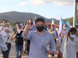fernando anselmo usa máscara e faz sinal com a mão para cima e atrás correligionários em caminhada usando máscaras e com bandeiras