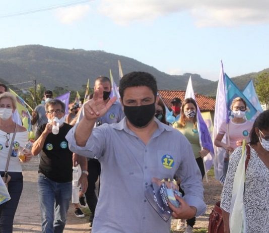 fernando anselmo usa máscara e faz sinal com a mão para cima e atrás correligionários em caminhada usando máscaras e com bandeiras