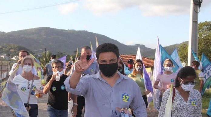 fernando anselmo usa máscara e faz sinal com a mão para cima e atrás correligionários em caminhada usando máscaras e com bandeiras